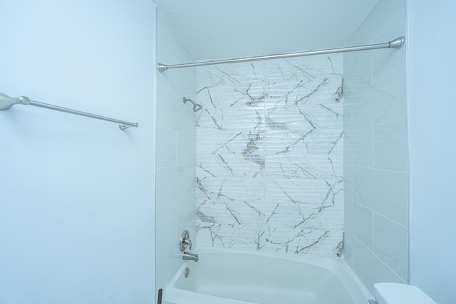 bathroom with toilet and tiled shower / bath