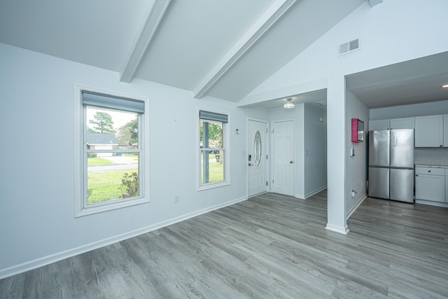 unfurnished living room with light wood-type flooring and lofted ceiling with beams