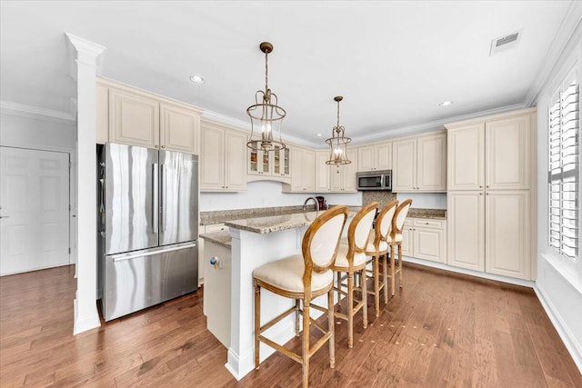 1003 Jervey Point Rd, Wando, SC 29492 - kitchen with stainless steel appliances, cream cabinets, crown molding, wood finished floors, and light stone counters
