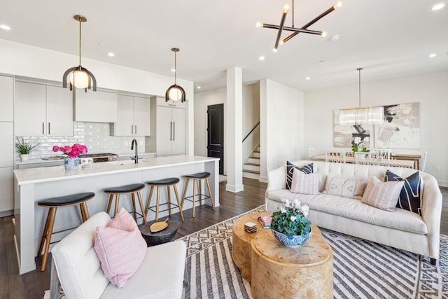 living room with a notable chandelier, sink, and dark wood-type flooring