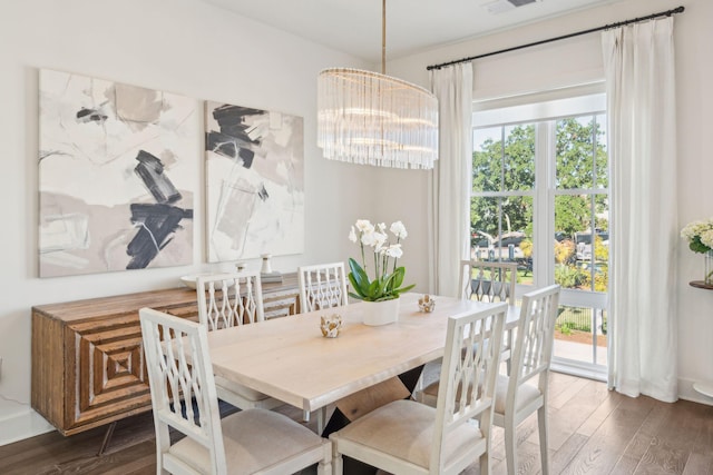 dining space with dark wood-type flooring and an inviting chandelier