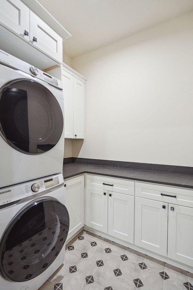 laundry area featuring stacked washer / drying machine and cabinets