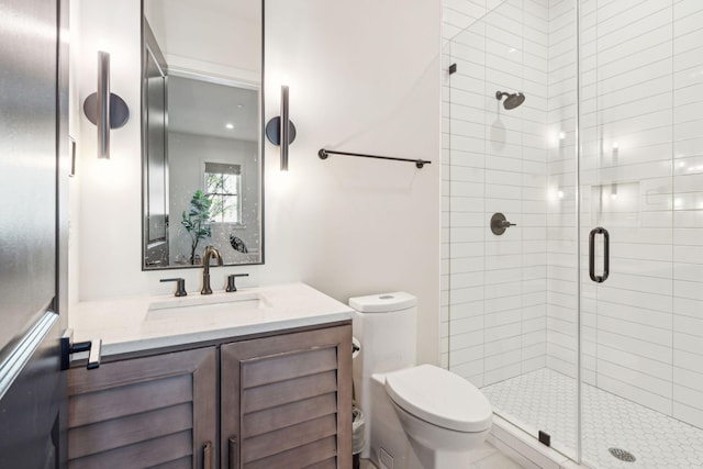 bathroom with vanity, a shower with shower door, and toilet