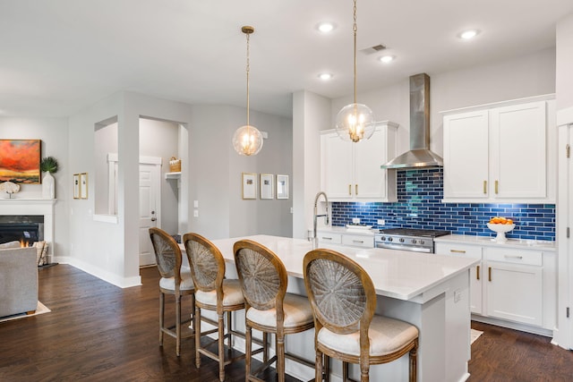 125 Integrity Ln, Charleston, SC 29492 - kitchen featuring wall chimney exhaust hood, stainless steel stove, light countertops, an island with sink, and backsplash