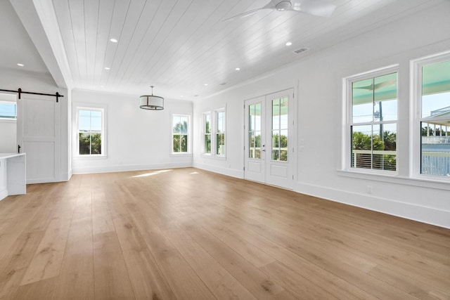 unfurnished living room with wood ceiling, a barn door, ceiling fan, and light wood-type flooring