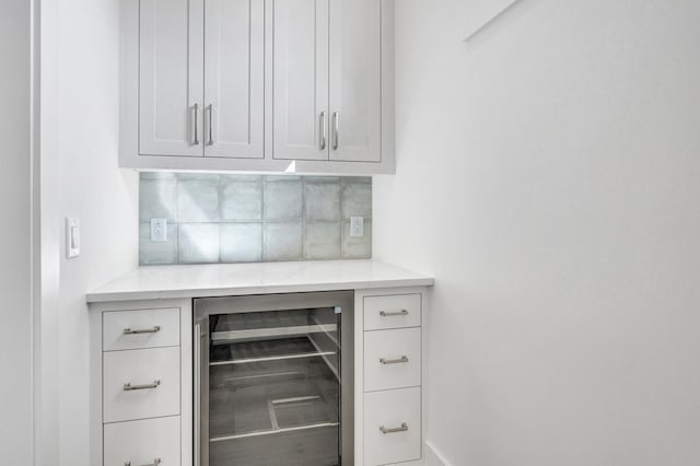 interior space with wine cooler, white cabinetry, and tasteful backsplash