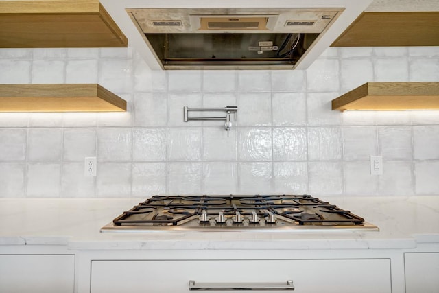 kitchen with stainless steel gas stovetop, extractor fan, tasteful backsplash, and white cabinetry