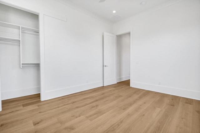 unfurnished bedroom with crown molding, light hardwood / wood-style floors, and a closet