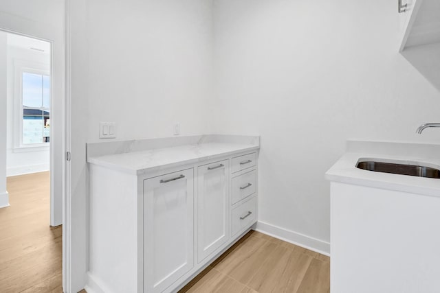 clothes washing area featuring sink and light hardwood / wood-style flooring