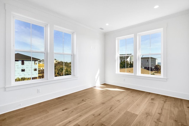 spare room featuring crown molding and light wood-type flooring