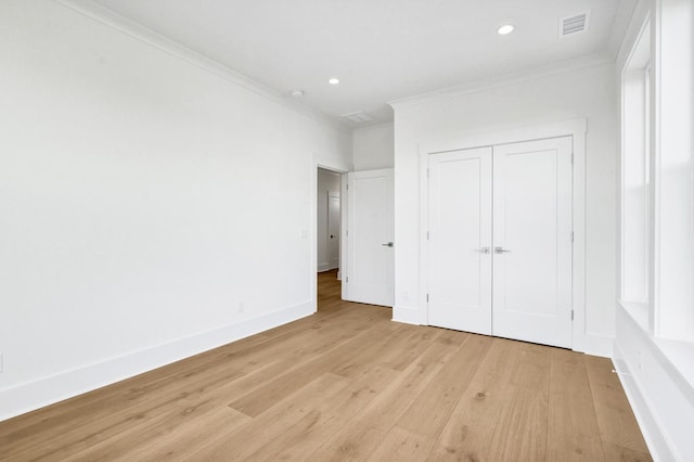 unfurnished bedroom with crown molding, a closet, and light wood-type flooring