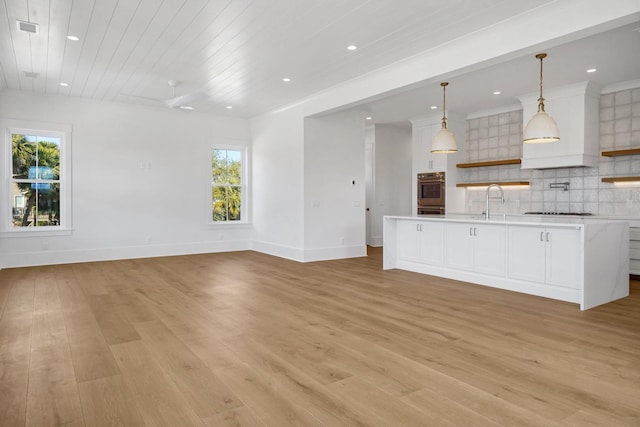 kitchen featuring white cabinetry, hanging light fixtures, backsplash, and light wood-type flooring