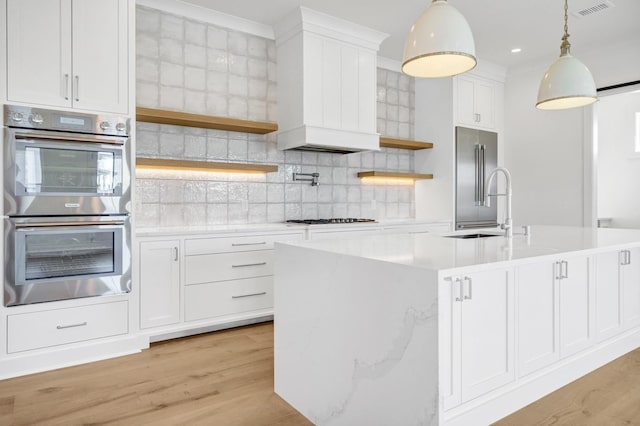 kitchen with sink, white cabinetry, a center island with sink, pendant lighting, and stainless steel appliances