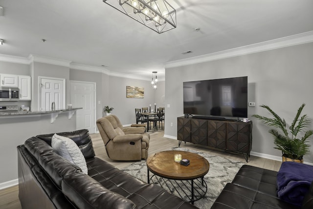 living room with a chandelier, light hardwood / wood-style floors, and ornamental molding