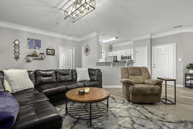 living room with a notable chandelier, light wood-type flooring, and crown molding