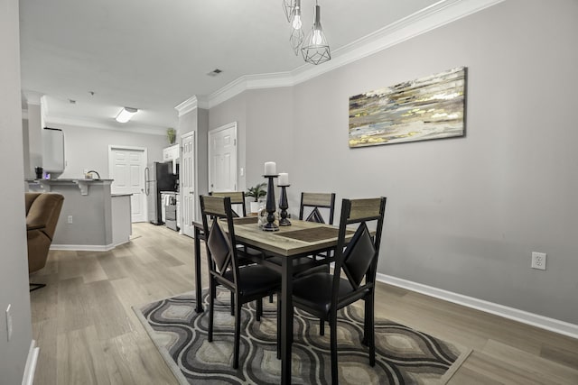 dining room with light wood-type flooring and ornamental molding