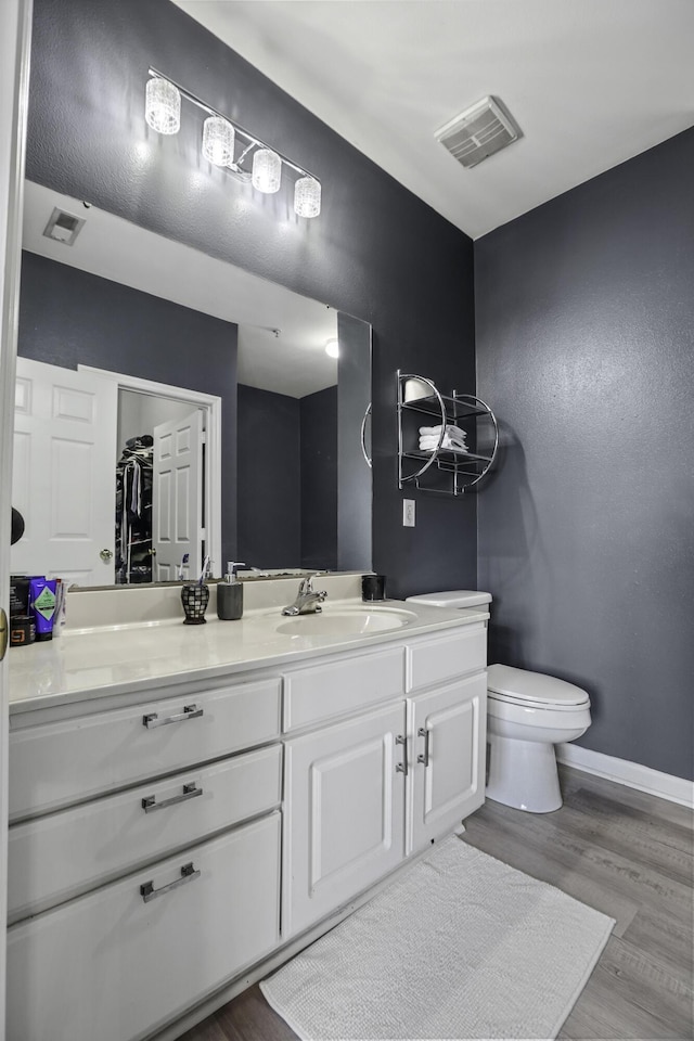 bathroom with hardwood / wood-style floors, vanity, and toilet