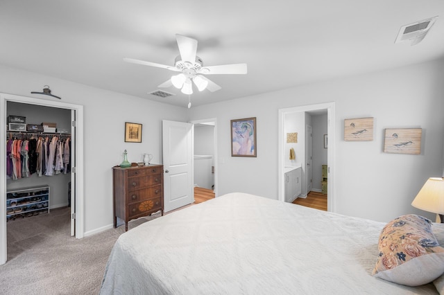 bedroom with a spacious closet, light carpet, a closet, and visible vents