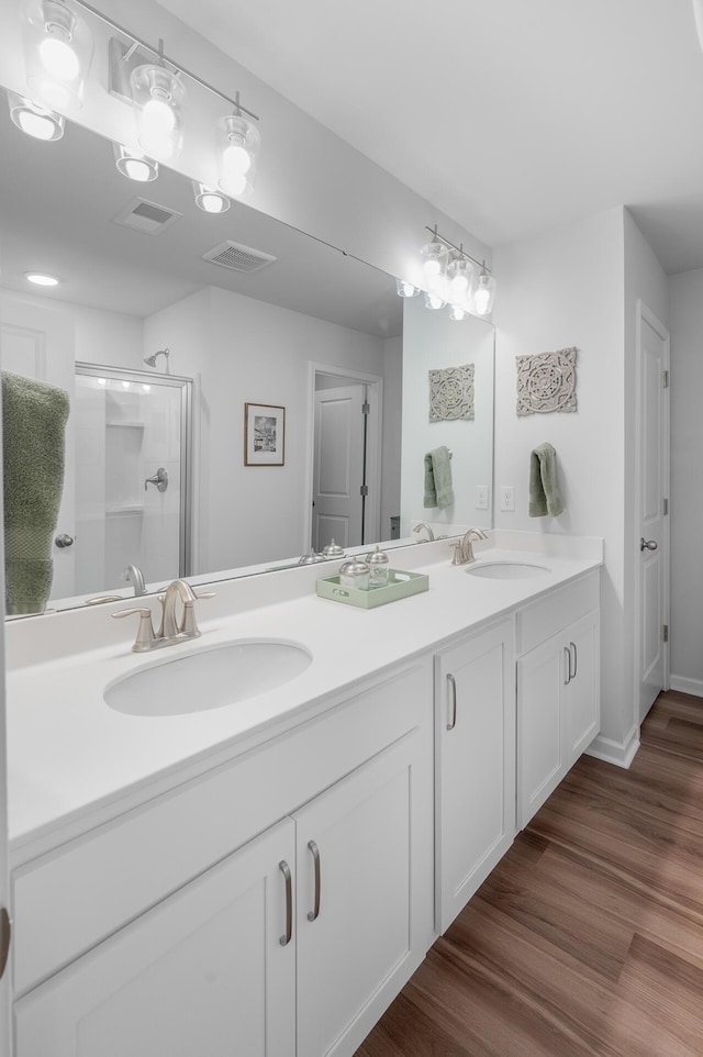 bathroom featuring visible vents, a sink, a shower stall, and wood finished floors