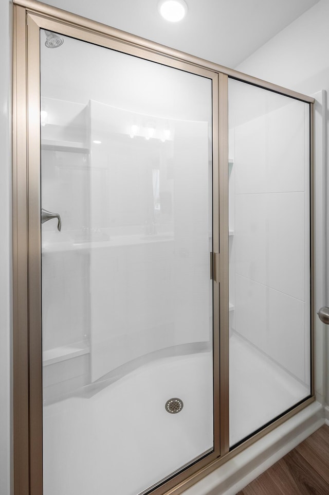 full bathroom featuring a stall shower and wood finished floors
