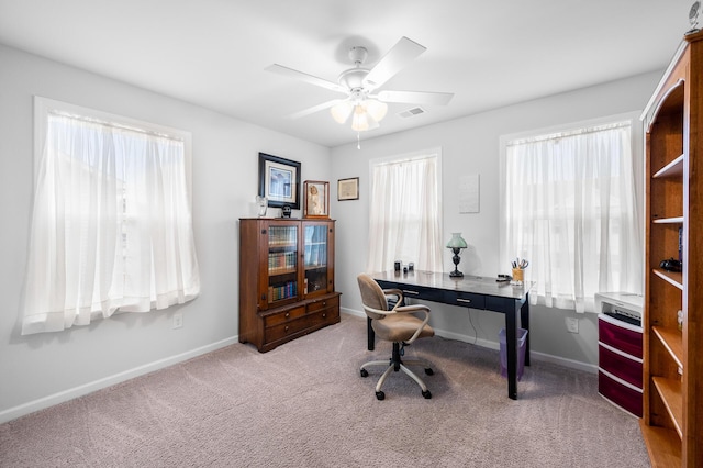 carpeted office space with baseboards, visible vents, and a ceiling fan