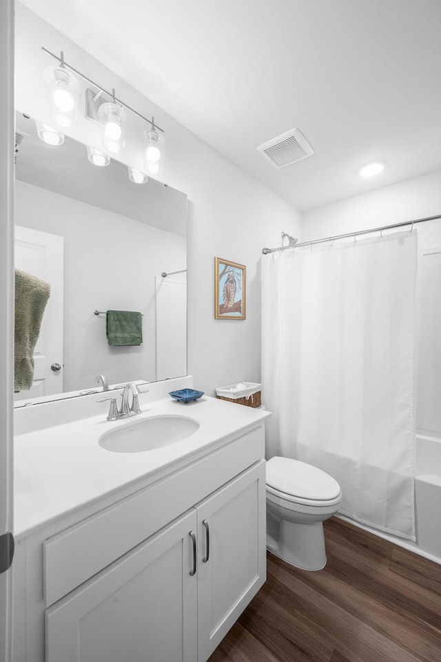 bathroom with vanity, shower / tub combo with curtain, toilet, visible vents, and wood finished floors