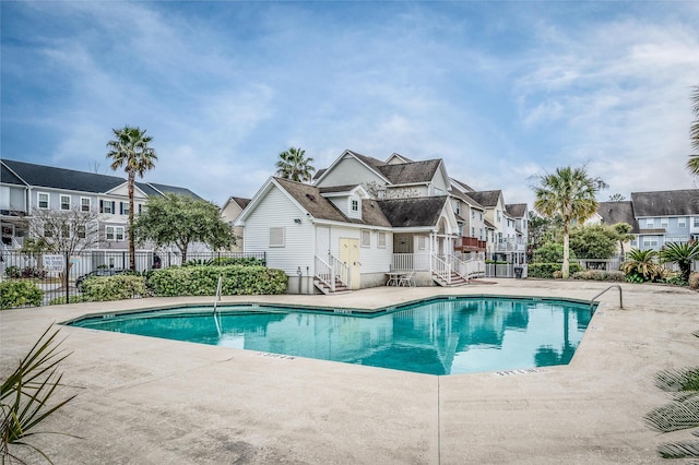community pool with a residential view, fence, and a patio