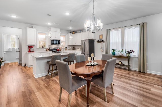dining space with an inviting chandelier, baseboards, and light wood-style floors