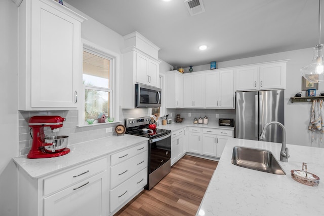 kitchen featuring visible vents, appliances with stainless steel finishes, white cabinetry, a sink, and backsplash