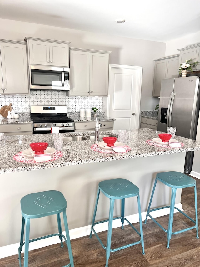 kitchen featuring appliances with stainless steel finishes, decorative backsplash, and light stone counters