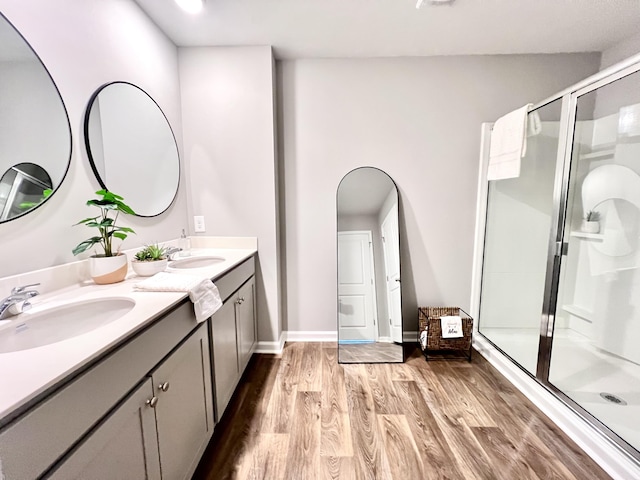 full bath featuring wood finished floors, a sink, and a shower stall