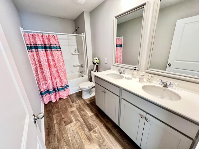 full bathroom featuring double vanity, a sink, toilet, and wood finished floors