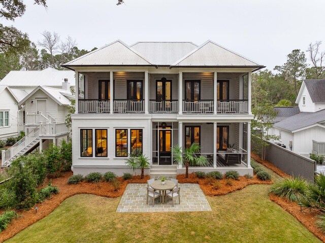 back of house with a lawn, a patio area, and a sunroom