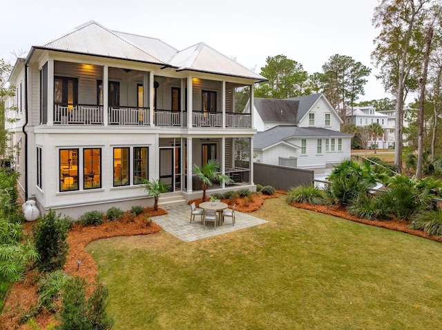 back of property with a balcony, a patio, a yard, and a sunroom