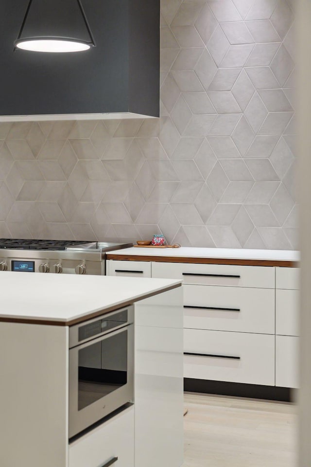 kitchen with stainless steel oven, white cabinets, and decorative backsplash