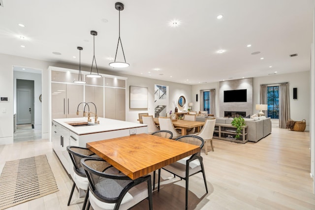 dining space with a fireplace, light hardwood / wood-style flooring, and sink