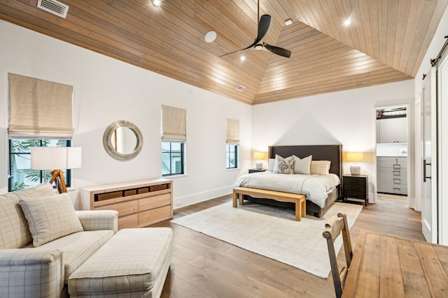 bedroom featuring high vaulted ceiling, a barn door, light hardwood / wood-style flooring, and wood ceiling