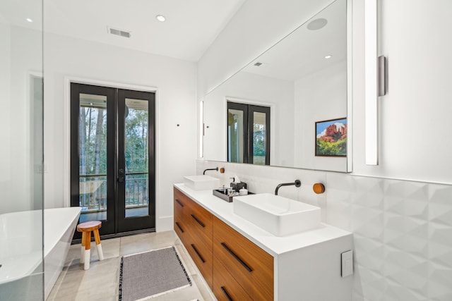 bathroom with french doors, vanity, a tub to relax in, and tasteful backsplash