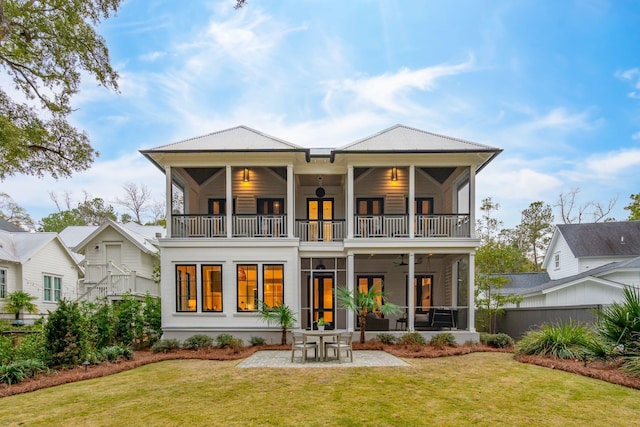 rear view of house featuring a balcony, a patio, ceiling fan, and a lawn