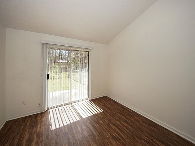 unfurnished room featuring dark hardwood / wood-style flooring and vaulted ceiling