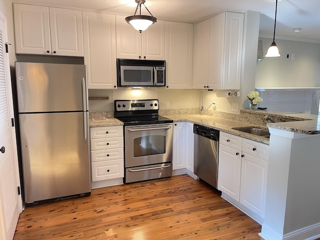 kitchen featuring appliances with stainless steel finishes, decorative light fixtures, white cabinets, kitchen peninsula, and light wood-type flooring