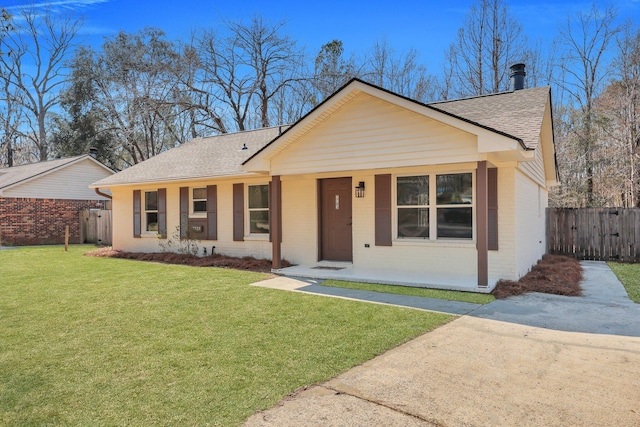 view of front of property with a shingled roof, a front yard, fence, and brick siding