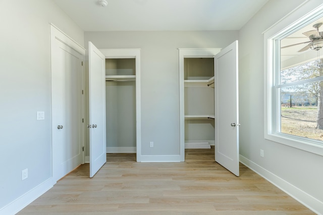 unfurnished bedroom with multiple closets, baseboards, and light wood finished floors