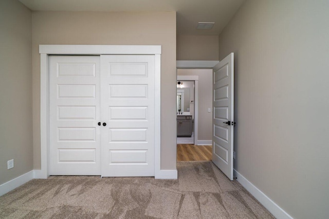 unfurnished bedroom featuring visible vents, carpet, a closet, and baseboards