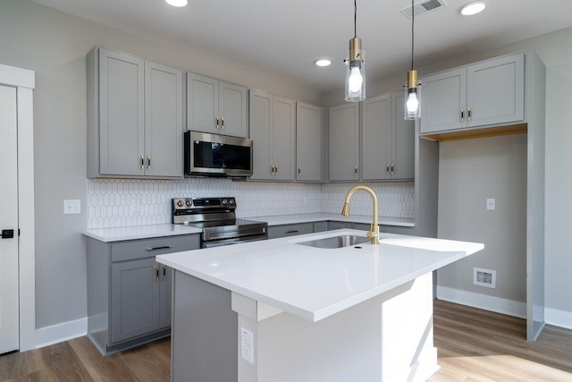 kitchen with decorative backsplash, appliances with stainless steel finishes, gray cabinetry, and a sink