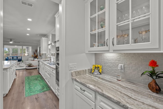 bar with visible vents, wood finished floors, oven, ceiling fan, and backsplash