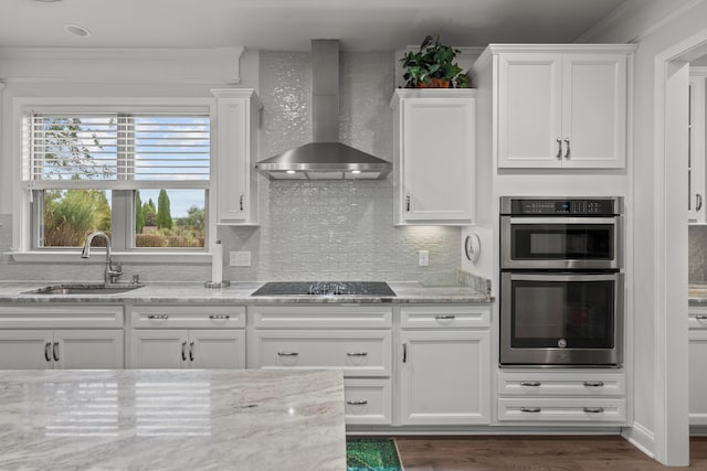 kitchen with wall chimney range hood, crown molding, a sink, double oven, and black electric cooktop