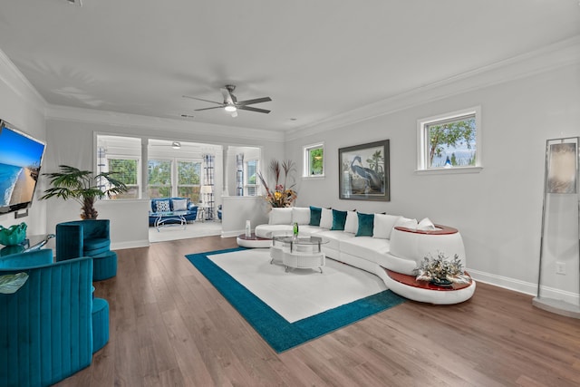 living room featuring plenty of natural light, baseboards, ornamental molding, and a ceiling fan