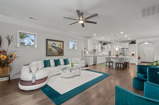 living area with visible vents, crown molding, and ceiling fan