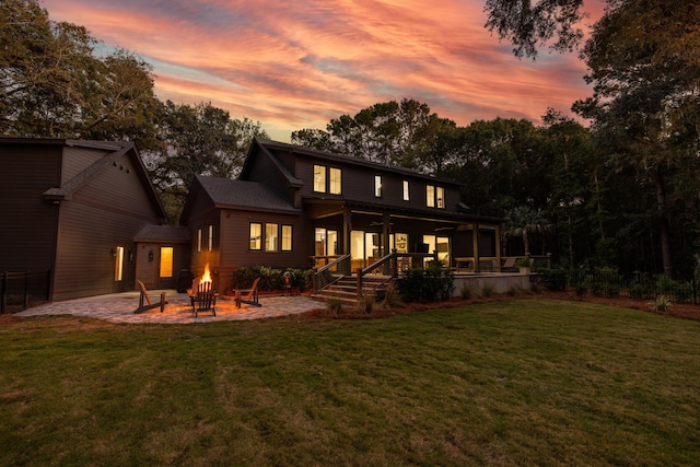 back house at dusk with a lawn, a patio, and a fire pit